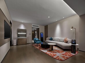 A modern living room with a sofa, a blue armchair, a coffee table, and a TV mounted on the wall. - Dhawa Xi'an Chanba (Xi'an)