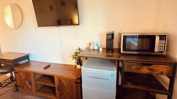 Una kitchenette compacta equipada con microondas, cafetera y refrigerador.
