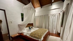 A bedroom with a wooden bed, white curtains, and a canopy bed. - Palay (Malay)