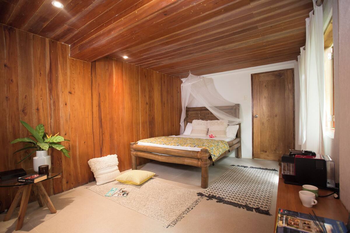 Un dormitorio con paneles de madera, una cama, una mesita de noche y una planta en maceta.