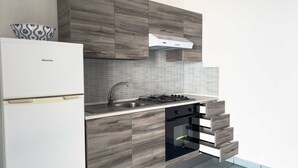 Una cocina moderna con un refrigerador blanco, una estufa a gas y armarios de madera.