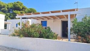 Una casa moderna con fachada blanca, una pérgola de madera y una puerta azul.