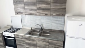 Una cocina con estufa a gas, lavaplatos doble y armarios de madera.