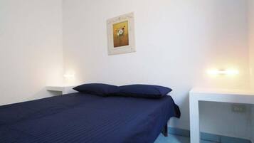 A room with a bed, two bedside tables, and a wall-mounted picture.