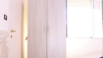 Une chambre à coucher avec un lit, une armoire, une télévision et une fenêtre.