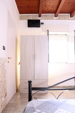 Ein Schlafzimmer mit einem Bett, einem Kleiderschrank, einem Fernseher und einem Fenster.