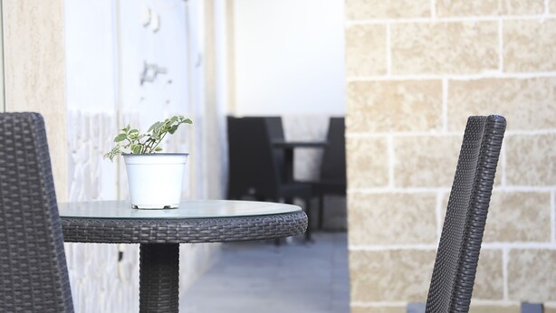 A wicker table with a potted plant, a chair, and a stone wall in the background. - Orchid Villa 1 with parking (Torre Lapillo)