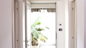 A hallway with a wooden ceiling, an air conditioning unit, and a door leading to a bright outdoor area with a banana plant. - Orchid Villa 1 with parking (Torre Lapillo)