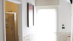 A bathroom with a shower, toilet, and a door leading to a dining area with a table and chairs. - Orchid Villa 1 with parking (Torre Lapillo)
