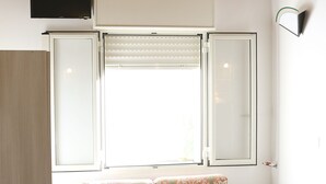 A room with a wooden ceiling, a sofa with patterned upholstery, a window with blinds, and a flat-screen TV mounted above the sofa. - Orchid Villa 1 with parking (Torre Lapillo)