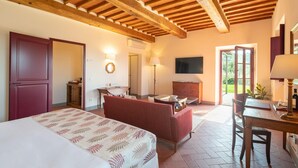Habitación de hotel con cama, sofá, mesa de comedor, televisor y chimenea.