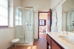 A modern bathroom with a glass-enclosed shower, a vanity with a large mirror, and a small stool. - The Club House (Castelnuovo Berardenga)