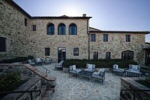Un edificio de piedra con un patio que cuenta con asientos al aire libre y una escalera.
