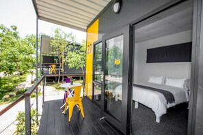 Una habitación de hotel moderna con una cama, una mesita y sillas afuera.