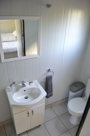 A bathroom with a sink, mirror, toilet, and a towel rack. - Sleepover Kruger Gate (Mbombela)