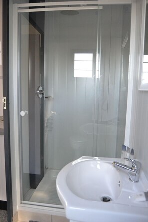 Een moderne badkamer met een douche met glazen wand, een wit wastafelmeubel en een spiegel.