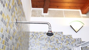 Een douche met een metalen hendel en een aan de muur bevestigde lamp.