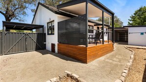 Ein modernes Haus mit überdachter Terrasse, umzäunter Garten und Garage.