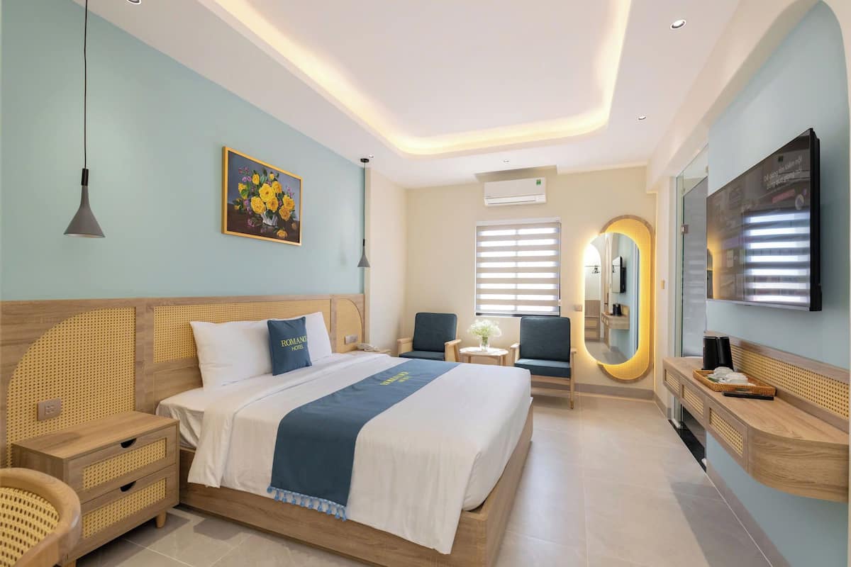 Una habitación de hotel moderna con una cama grande, mesitas de noche, un escritorio y una zona de estar.