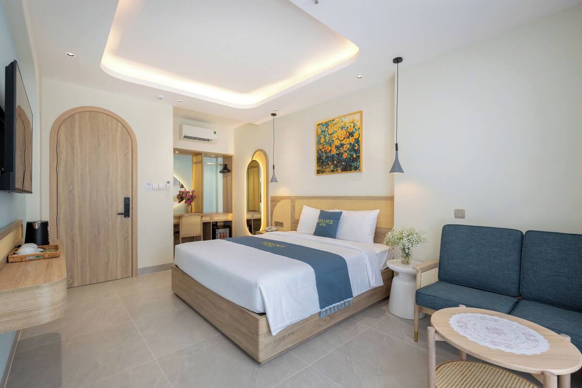 Una habitación de hotel moderna con una cama grande, un sofá, una mesita y un televisor.