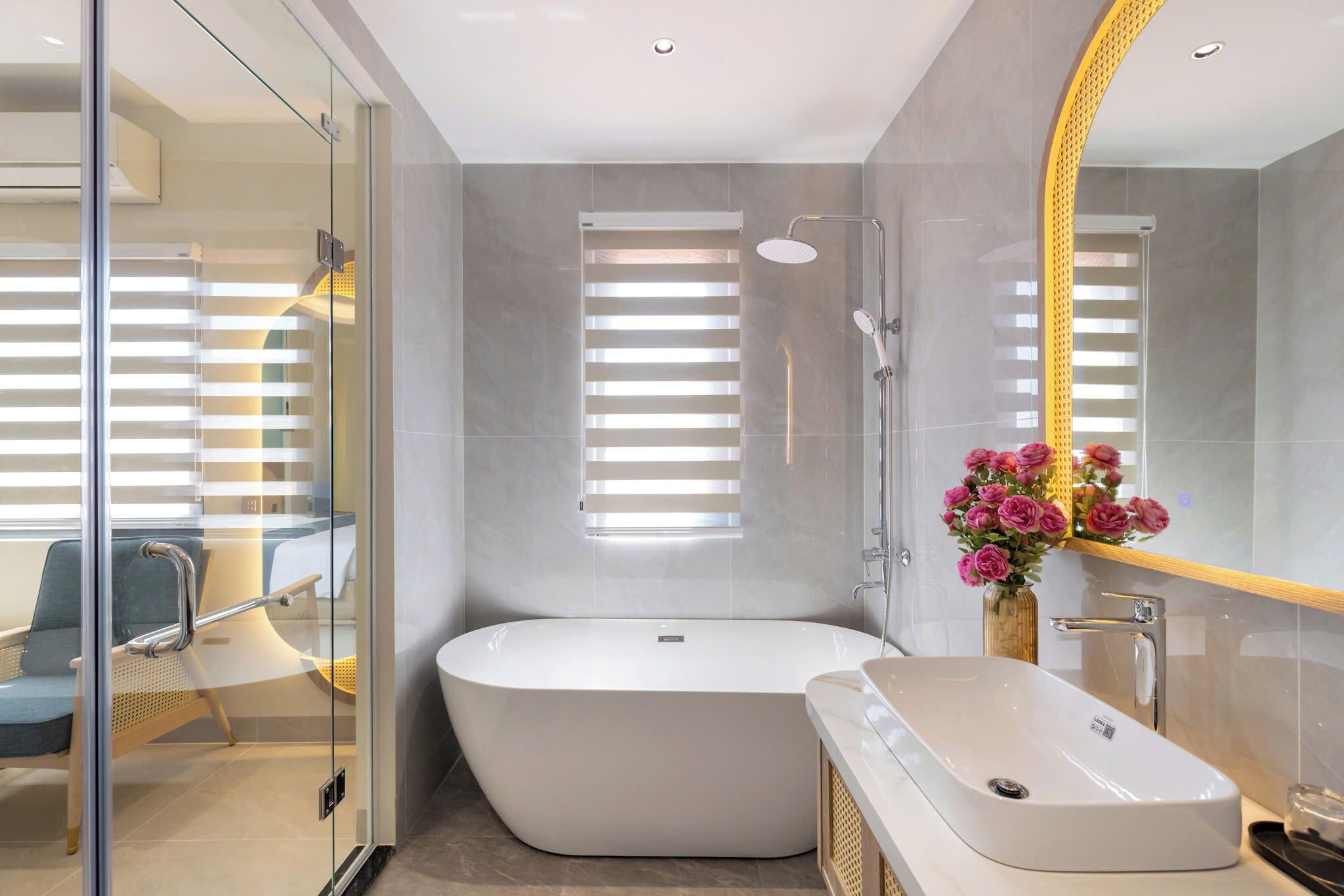 Un baño moderno con una bañera independiente, un tocador con lavamanos y un espejo grande.