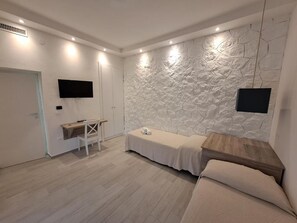 Une chambre avec un mur en pierre, un lit, un bureau et un téléviseur.