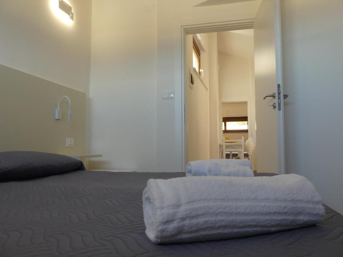 A hotel room with a bed, a bedside table, a wall-mounted light, and a door leading to a bathroom.