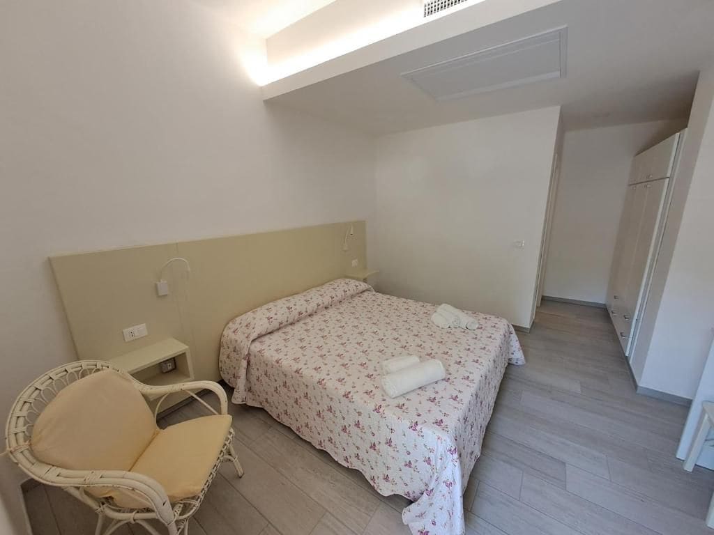 A bedroom with a bed, a chair, a nightstand, and a wardrobe.
