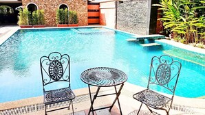 Ein Swimmingpool mit zwei verzierten Metallstühlen und einem kleinen Tisch.