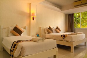 Two twin beds with white bedding and brown pillows, a wall-mounted lamp, and a window with curtains. - Grandsmile Welnez Condo Pattaya (Pattaya)
