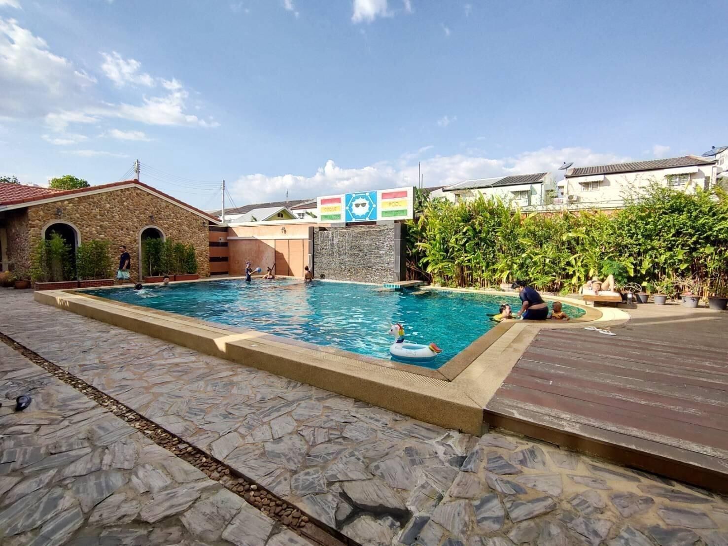 Una piscina con baldosas de piedra, un muelle de madera y un edificio de piedra con arcos.