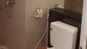 A bathroom with a toilet, a shower, and a towel rack. - Grandsmile Welnez Condo Pattaya (Pattaya)
