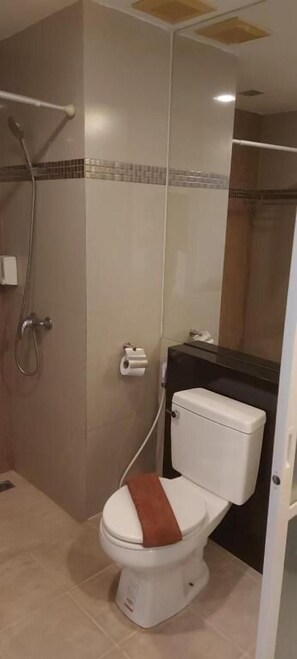 A bathroom with a toilet, a shower, and a towel rack. - Grandsmile Welnez Condo Pattaya (Pattaya)
