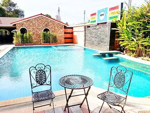 A swimming pool with two ornate metal chairs and a small table. - Grandsmile Welnez Condo Pattaya (Pattaya)