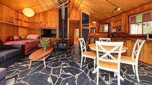 Ein gemütliches Blockhaushaus-Interieur mit Wohnbereich, Esstisch und Küche.