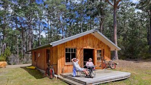 Eine Holzjagdhaushütte mit Veranda, einem Fahrrad und einem kleinen Tisch.