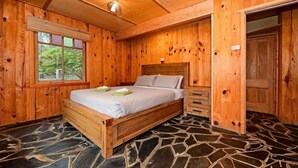 Ein Zimmer mit Holzboden, einem Bett und einem Fenster mit Jalousien.
