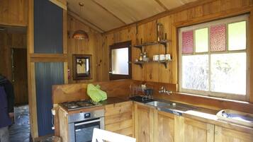 Cocina de cabaña de madera con estufa, horno, lavaplatos y ventana con vidrio emplomado.