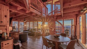 Interno di una baita di legno con zona pranzo, angolo cottura e salottino.