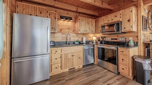 Una cucina in stile baita in legno, con frigorifero in acciaio inossidabile, forno a microonde, forno e lavastoviglie.
