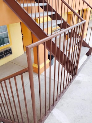 A multi-level building with a brown metal railing and yellow walls.
