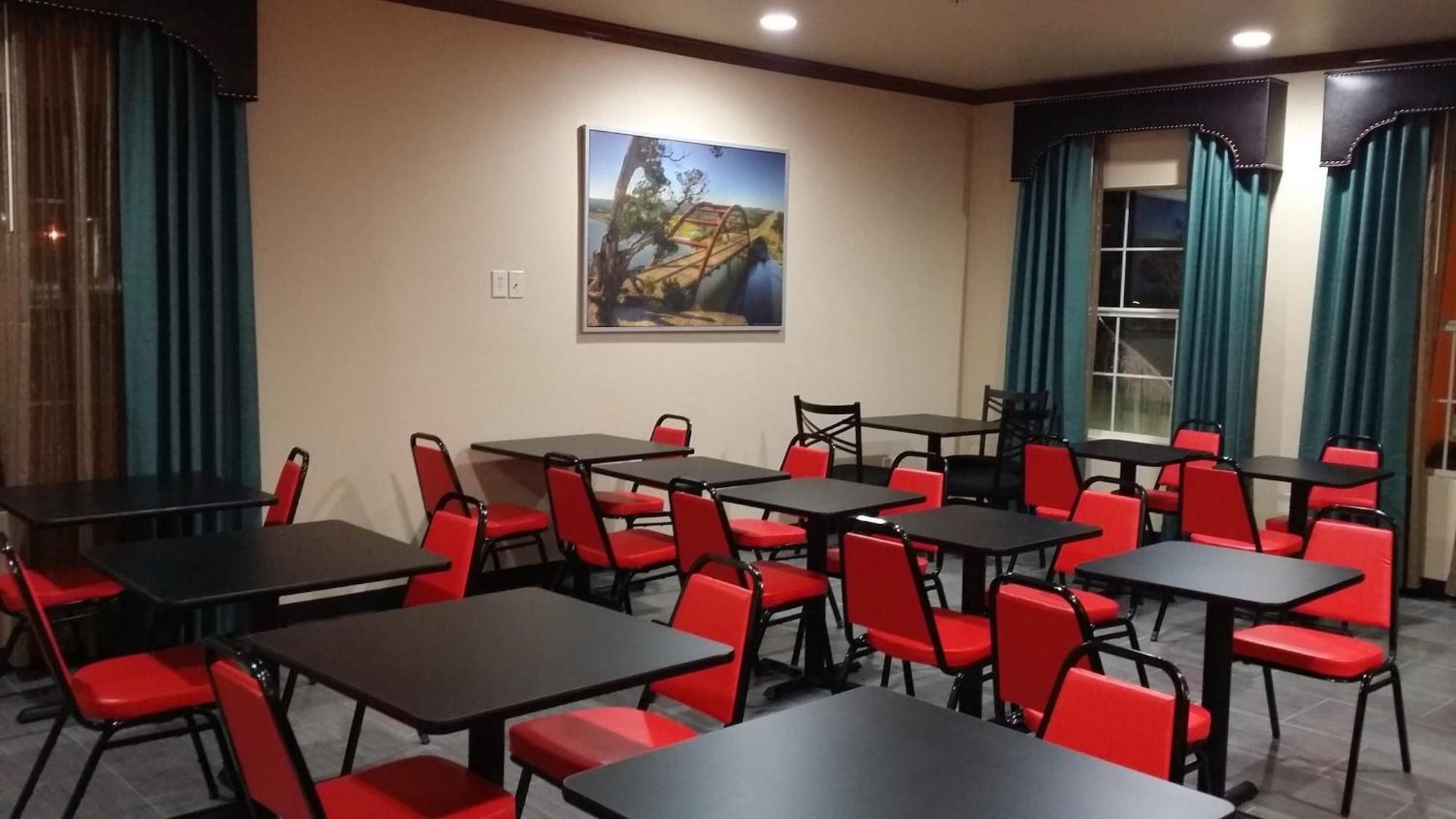 A conference room with tables and chairs, a painting on the wall, and curtains on the windows.