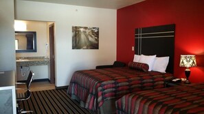 A hotel room with a bed, a nightstand, a lamp, a painting on the wall, and a bathroom with a mirror and sink.