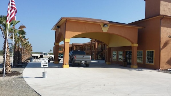 A building with a large entrance covered by an arch, a sign indicating parking for trucks and trailers, and an American flag.
