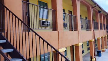 A multi-story building with a yellow facade, multiple balconies, and a staircase leading to the upper floors.