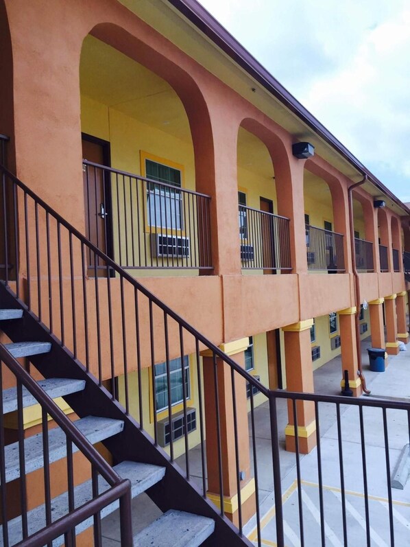 A multi-story building with a yellow facade, multiple balconies, and a staircase leading to the upper floors.