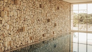 A room with a stone wall and a large window. - Es Racó D Artá (Arta)