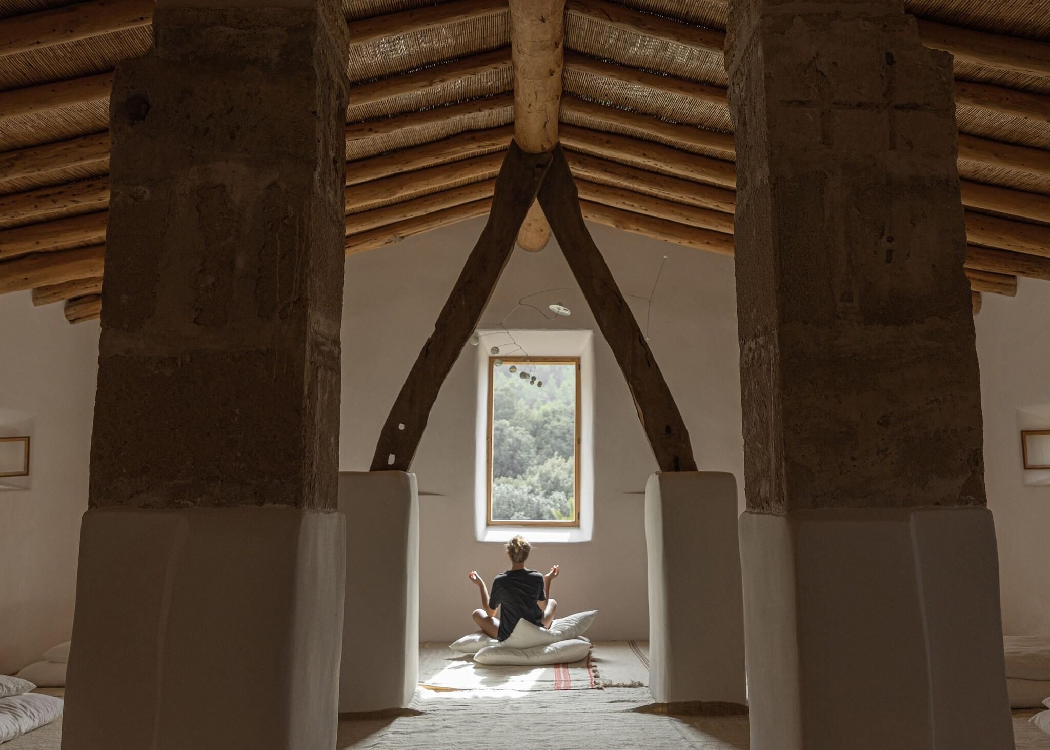 Una habitació amb un sostre alt, bigues de fusta i una finestra gran.