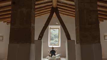 Una habitació amb un sostre alt, bigues de fusta i una finestra gran.