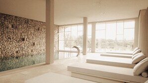 A modern interior with a stone wall, large windows, and a pool area. - Es Racó D Artá (Arta)